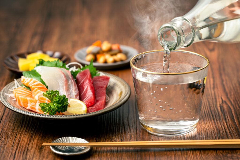 Shochu served oyuwari in a clear glass alongside sashimi and side dishes